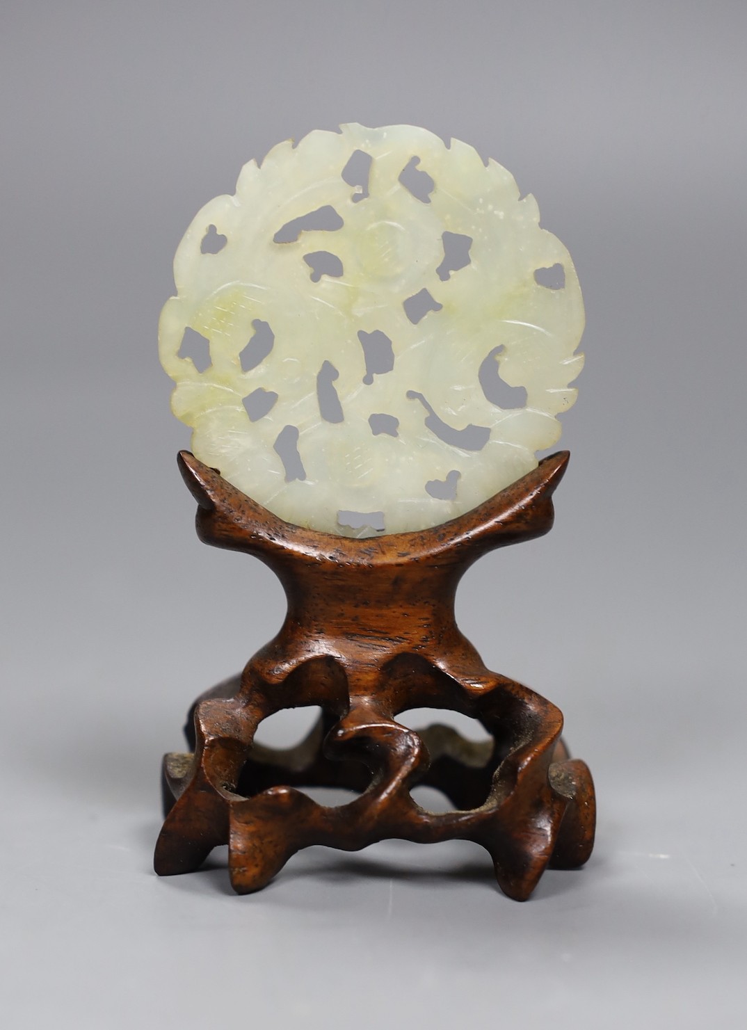 A Chinese jade disc and wood stand, 9cms high